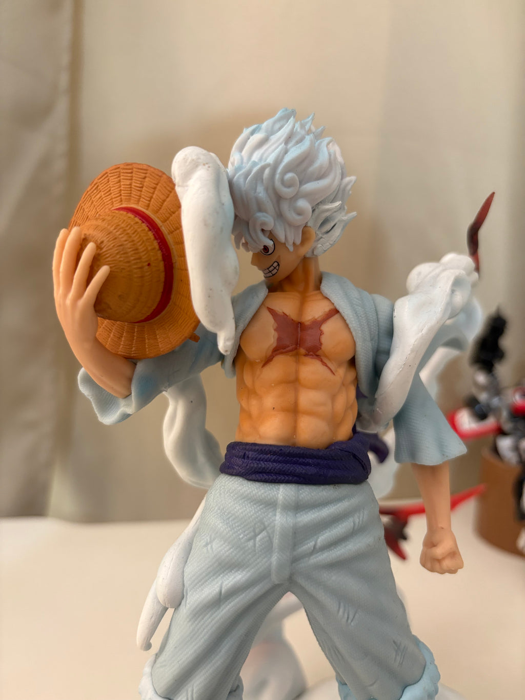 Close-up of Luffy Gear 5 laughing face, white flame hair, and woven straw hat held in hand